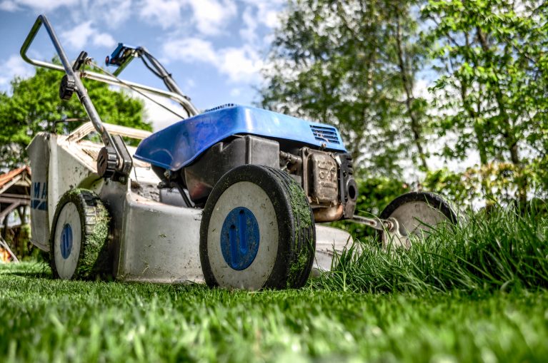 Blue lawn mower on green grass