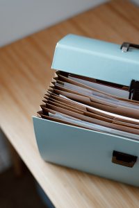 a light blue folder with archived office files sitting on a brown wooden table.