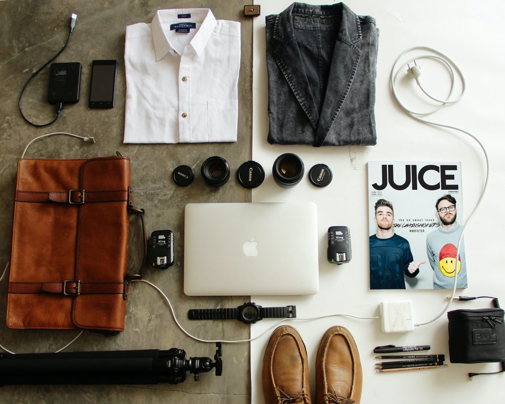 flat lay of misc items such as an apple macbook and magazine 