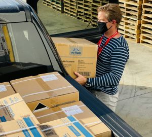 man in a black and white striped top loading boxes into his car